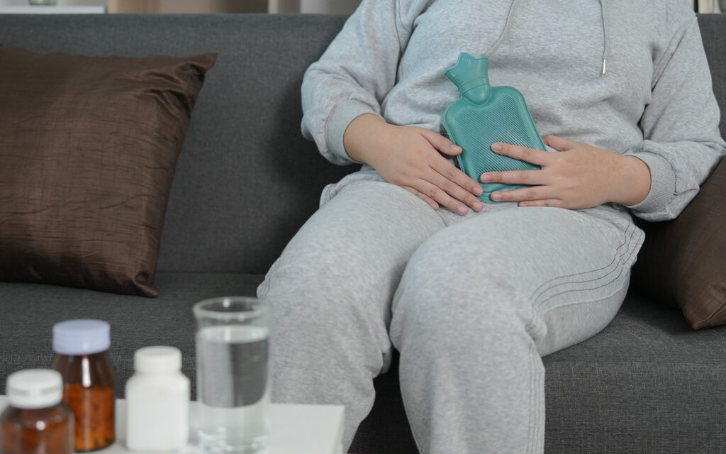 Woman with stomach pain, drugs and water